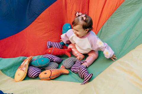 Olívia brincando em um espaço colorido com brinquedos durante a festa.'