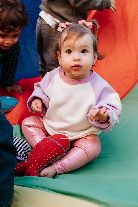 Olívia sentada em um brinquedo colorido durante a festa de 1 ano.'