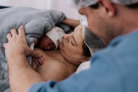 Jessica contempla Maria Clara aconchegada em seus braços enquanto Fabricio acompanha o primeiro encontro entre mãe e filha.'