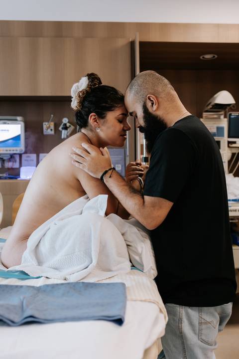 Bruno acolhe Yasmin com um beijo carinhoso na testa, oferecendo apoio durante o trabalho de parto.'