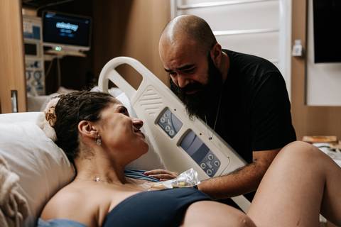 Yasmin e Bruno trocam olhares e sorrisos durante o trabalho de parto, compartilhando a expectativa pela chegada da filha.'