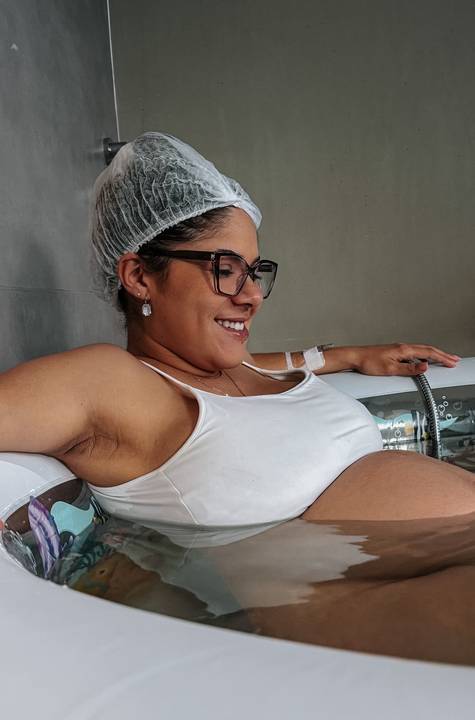Yasmin sorri durante o trabalho de parto, acompanhada pela equipe médica e cercada de cuidados.'