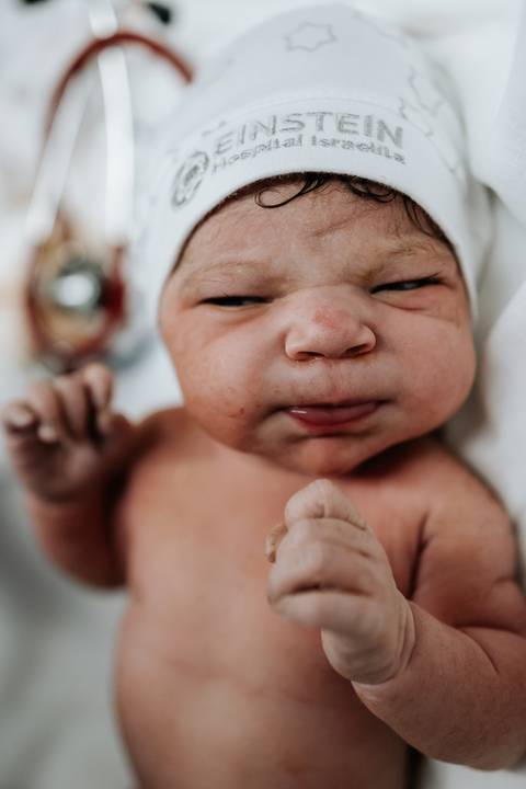 Julieta recém-nascida aparece deitada, com os olhos fechados e as mãos próximas ao rosto.'