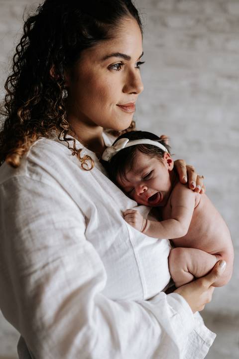 Mamãe Yasmin acolhendo Julieta no colo, em um momento de carinho e aconchego.'