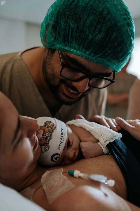 Samuel admirando a filha recém-nascida e acariciando delicadamente seu rostinho.'