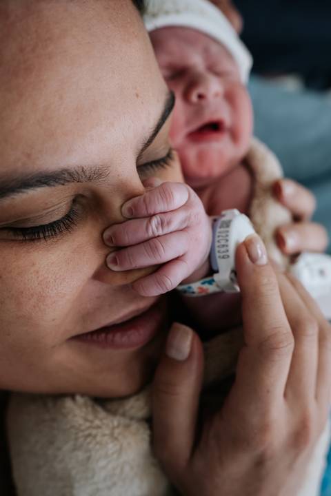 Marina de olhos fechados a beijar com carinho a mãozinha do bebé José Joaquim.'