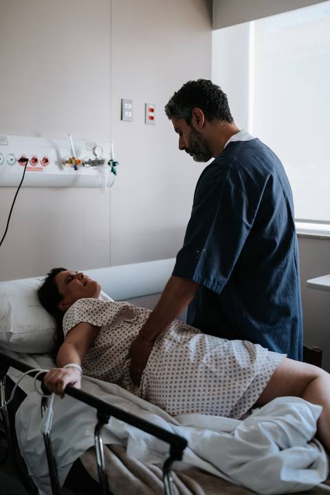 José Carlos inclinado sobre a cama amparando e dando apoio a Marina no quarto.'