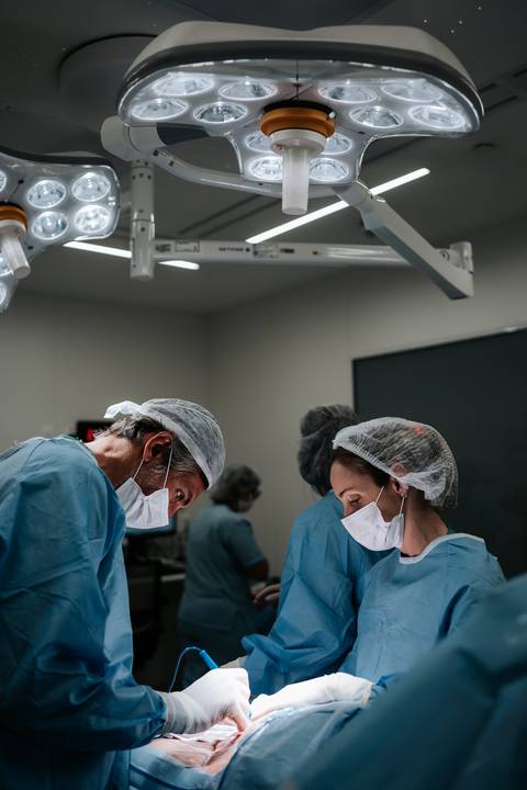 Equipa médica atenta e reunida na sala de cirurgia durante o parto.'