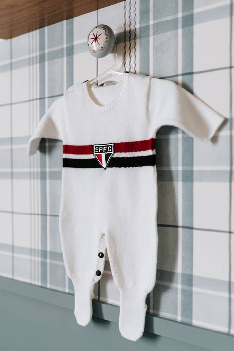 Detalhe do macacãozinho branco do São Paulo Futebol Clube pendurado.'