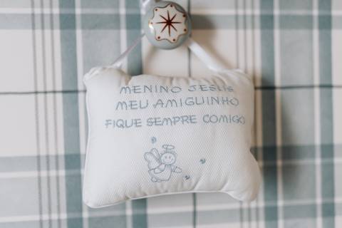 Almofadinha com oração do Santo Anjo em tecido xadrez na parede do quarto.'