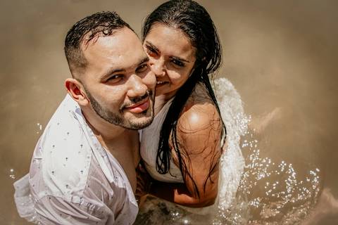 Casal dentro da água na praia'