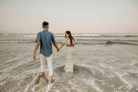 Casal caminhando para dentro do mar'