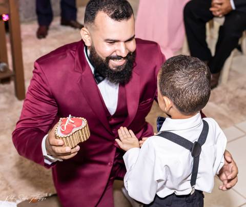 O noivo recebe as alianças com muita euforia e emoção das mãos do pequeno par gio.  '