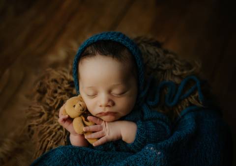 foto newborn de bebê segurando urso'