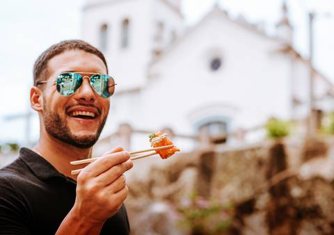 homem sorrindo segurando sushi'