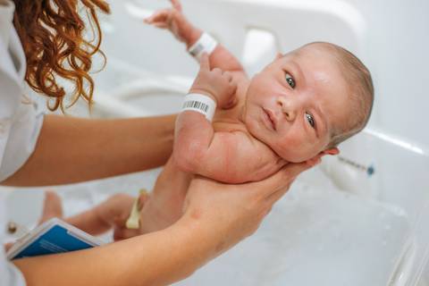 olhar atento do bebê durante o primeiro banho na maternidade'
