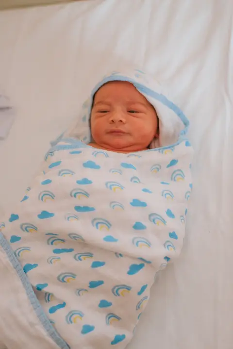 bebê enrolado na toalha após primeiro banho na maternidade'