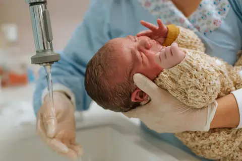 enfermeira lavando os cabelos do bebê'