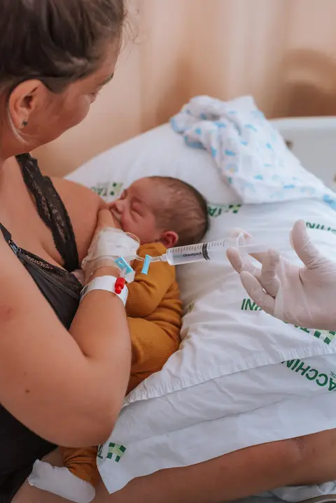 mamãe recebendo medicação intravenosa após parto e amamentando bebê recém-nascido'