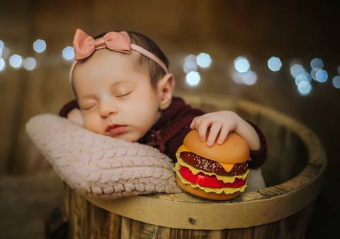 bebê segurando hamburguer durante ensaio newborn'