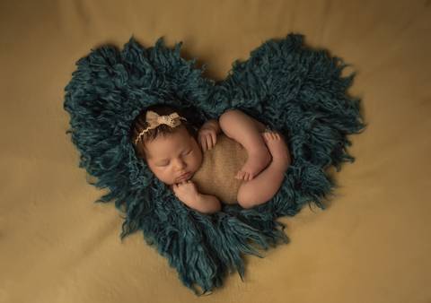 bebê deitada em coração feito com pêlo no ensaio newborn'