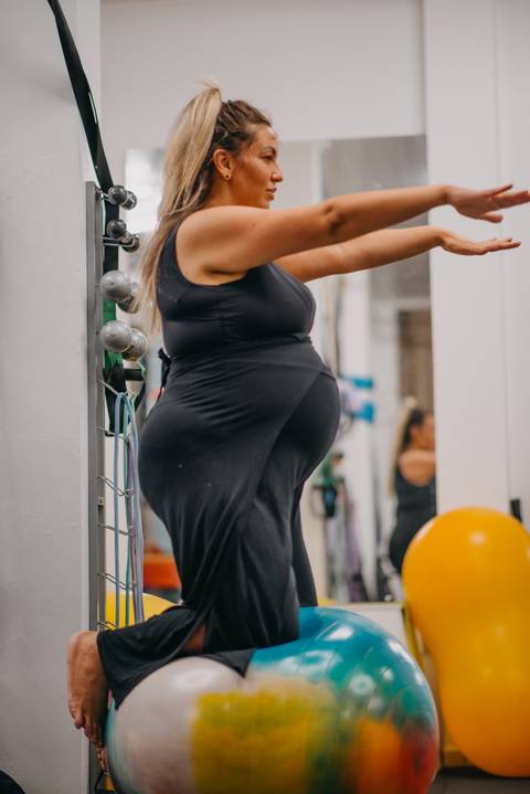 gestante se equilibrando de joelhos sobre bola de pilates'