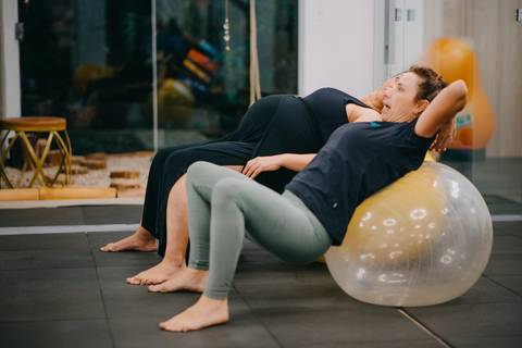 instrutora mostrando exercício pélvico para gestante na bola de pilates'