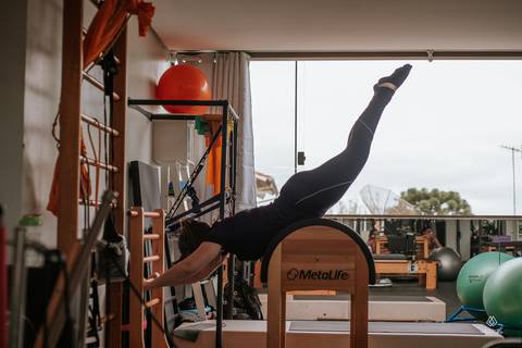 mulher fazendo exercício em equipamento de pilates em frente a janela'