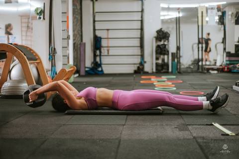 mulher deitada no chão fazendo exercícios em academia'