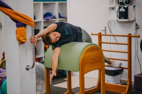 instrutora demonstrando exercício em aparelho de pilates'