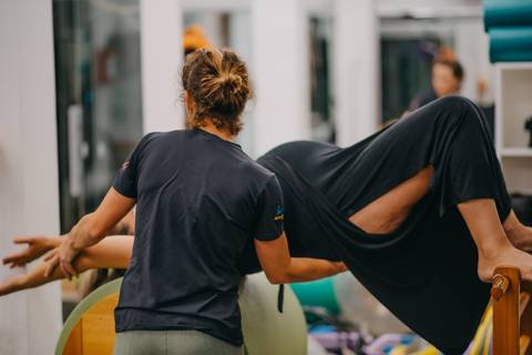 instrutora mostrando posicionamento para gestante em aparelho de pilates'