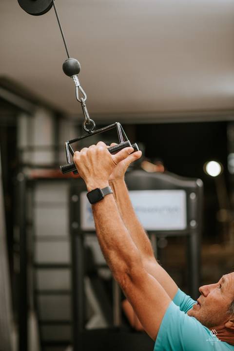 homem fazendo exercício de puxada alta em academia'