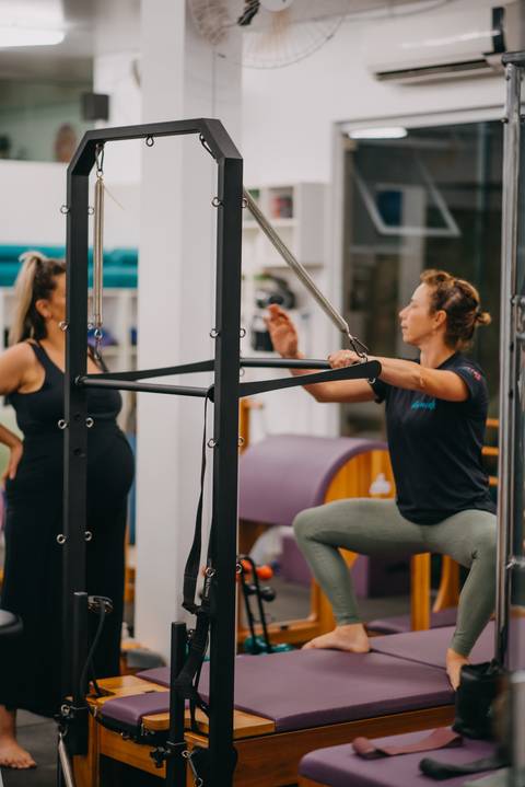 instrutora mostrando exercício em aparelho de pilates para gestante'