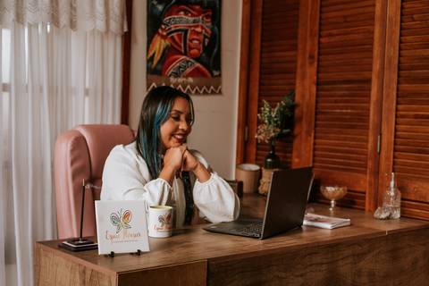 mulher sentada frente ao notebook sorrindo'