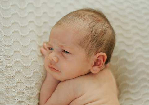 foto newborn de bebê com olhos abertos em close do rostinho em ensaio newborn de recém-nascido'