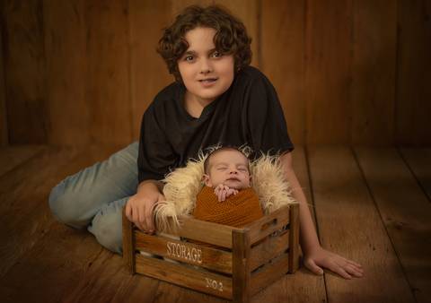 foto de bebê em caixote enrolado em wrap com irmão em ensaio newborn de recém-nascido'