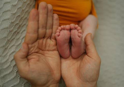 detalhe de pezinhos do bebê em comparação as mãos do pai em ensaio newborn de recém-nascido'