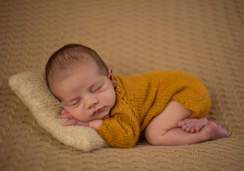 bebê em pose de ladinho com travesseiro em ensaio newborn de recém-nascido'
