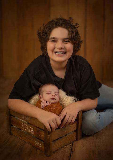menino sorrindo abraçando irmão em ensaio newborn de recém-nascido'