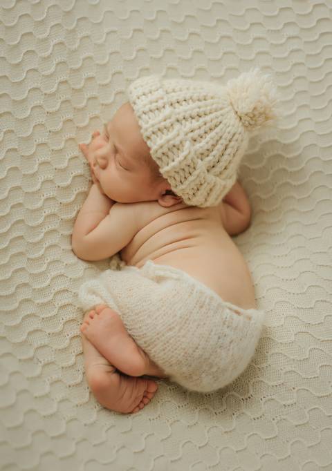 bebê de ladinho com touquinha em ensaio newborn de recém-nascido'