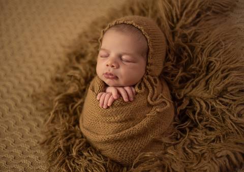 bebê enrolado em wrap e com touquinha em ensaio newborn de recém-nascido'
