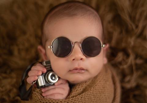 bebê com óculos escuros e câmera  em ensaio newborn de recém-nascido'