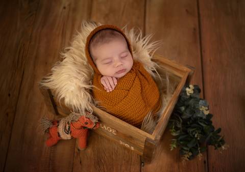 foto de bebê em caixote enrolado em wrap'