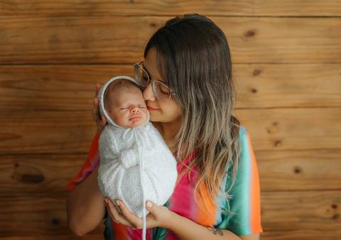 mãe dando cheirinho no bebê em ensaio newborn'