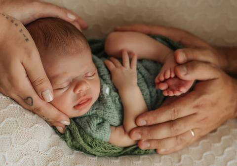 mãos dos pais ao redor do bebê'