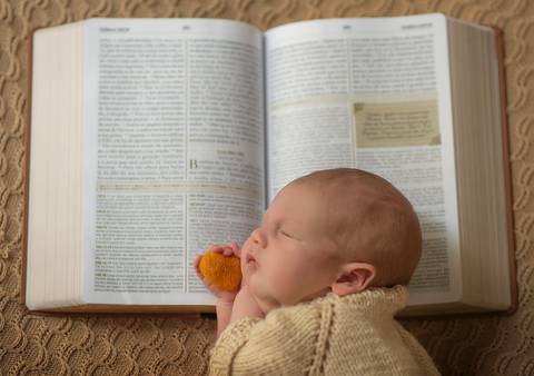 bebê deitado sobre bíblia aberta'