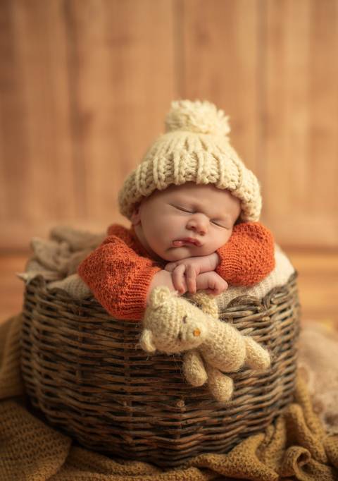 bebê  deitado sobre os bracinhos dentro de cesto'