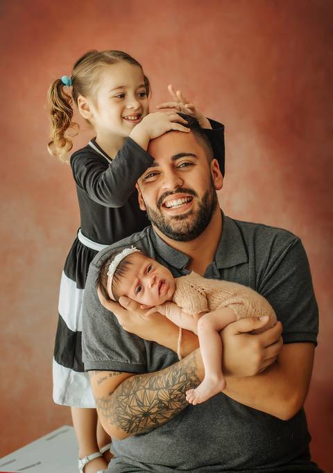 menina bagunçando pai e bebê fazendo careta no ensaio newborn'