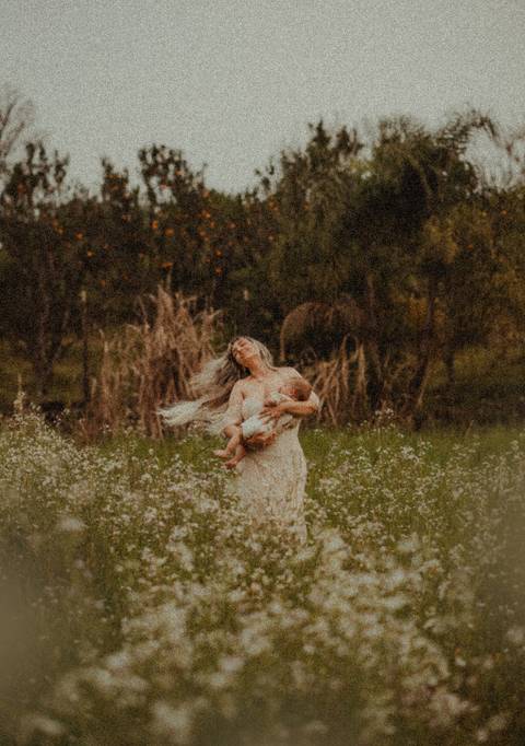 mulher com cabelos ao vento enquanto amamenta'