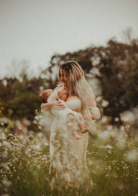 bebê tocando rosto da mãe durante a amamentação'